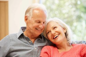 An older couple smiling and leaning into each other
